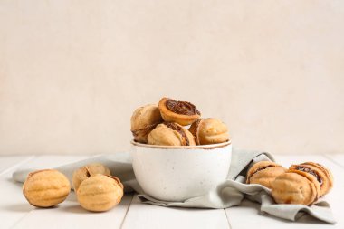 Beyaz ahşap masada kaynamış konsantre sütle ceviz şeklinde kurabiyeler.