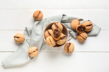 Beyaz ahşap arka planda kaynamış konsantre sütle ceviz şeklinde kurabiyeler.