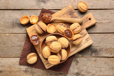 Tahta kesme tahtası ve bir kase tatlı ceviz şekilli kurabiye ve ahşap zemin üzerinde kaynatılmış konsantre süt.