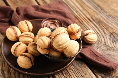 Tabak ve bir kase tatlı ceviz şekilli kurabiye ve ahşap zemin üzerinde kaynatılmış konsantre süt.