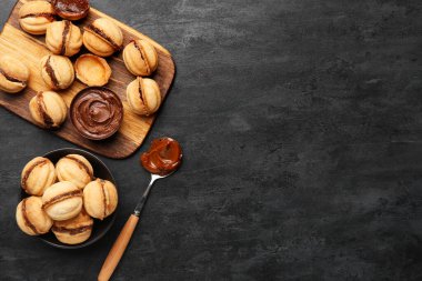 Ahşap tahta ve bir kase tatlı ceviz şekilli kurabiye ve siyah arka planda kaynamış konsantre süt.