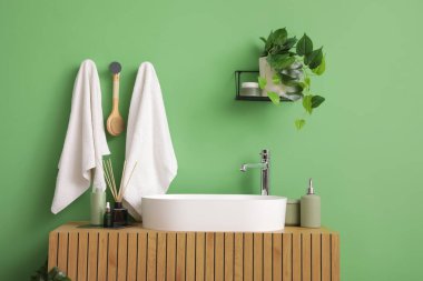 Banyoda yeşil duvarda asılı duran masaj fırçası olan havlular.