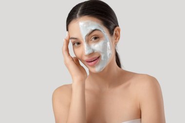 Beyaz arka planda yüz maskesi olan güzel genç bir kadın, yakın plan.