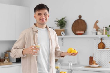 Mutfakta bir bardak su ve limonlu genç adam.
