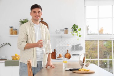 Elinde sürahi ve bir bardak limonlu su olan genç adam mutfakta.