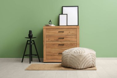 Odadaki yeşil duvarın yakınındaki gri puf ve sandık.