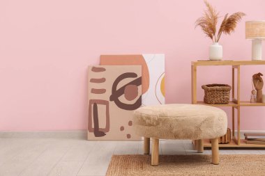 Dekorlu raflar, resimler ve pembe duvarın yanındaki bej pul.