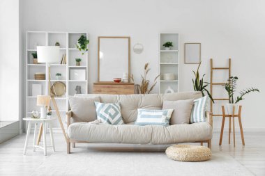 Bej kanepe, lamba ve bitkilerle aydınlık oturma odasının içi