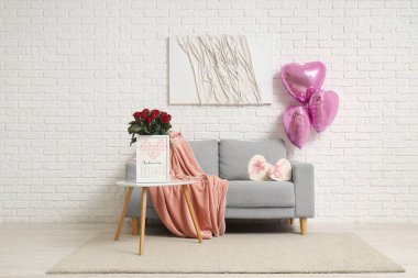 İçinde gri kanepe, güller, takvim ve kalp şeklinde balonlar olan festival salonu. Sevgililer Günü kutlaması