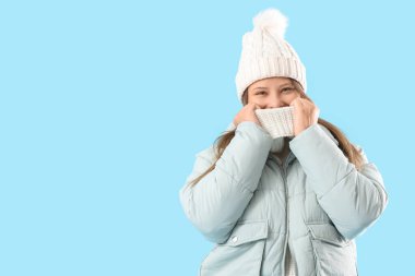 Young woman in winter clothes on blue background