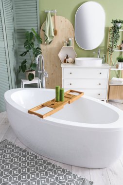 Banyonun içinde küvet, lavabo ve yeşil katlama ekran var.