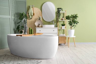 Banyonun içinde küvet, lavabo ve yeşil katlama ekran var.