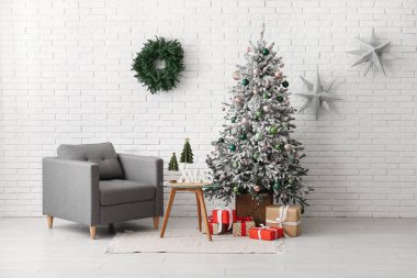 Oturma odasının içinde Noel çelengi, koltuk ve köknar ağacı var.