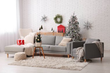 Oturma odasının içinde Noel ağaçları, kanepe ve koltuk var.