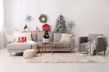 Oturma odasının içinde Noel ağaçları, kanepe ve koltuk var.
