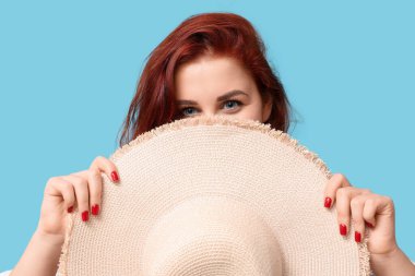 Mavi arka planda şapkası olan güzel kızıl saçlı kadın.