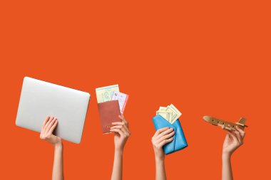 Modern dizüstü bilgisayarı, ahşap uçağı, cüzdanı ve renkli arka planı olan kadın eli.