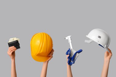 Female hands with construction tools and wallet on grey background clipart