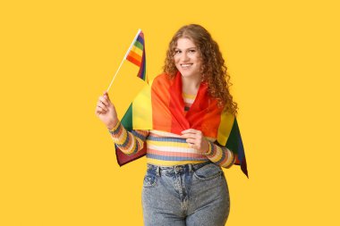 Sarı arka planda LGBT bayrakları olan güzel genç bir kadın.