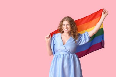 Pembe arka planda LGBT bayrağı olan güzel genç bir kadın.
