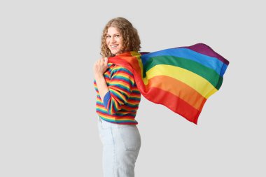 Gri arkaplanda LGBT bayrağı olan güzel genç bir kadın.