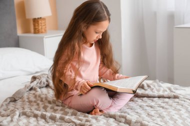 Evde İncil okuyan tatlı küçük bir kız.