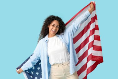 Mavi arka planda Amerikan bayrağı olan mutlu Afro-Amerikan kadın.