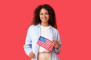 Kırmızı arka planda Amerikan bayrağı olan mutlu Afro-Amerikan kadın.