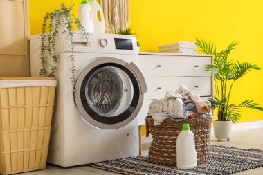 Çamaşır makinesi, çekmeceler ve kirli çamaşırlarla dolu bir sepet.