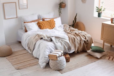 Yatak odasının içinde bavulla büyük, rahat bir yatak ve puf.