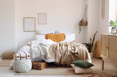 Yatak odasının içinde bavulla büyük, rahat bir yatak ve puf.