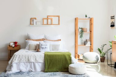 Muffin, komodin, raflar ve yatak odasının içi puf dolu büyük, rahat bir yatak.