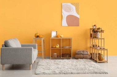 Sonbahar dekoru, kanepesi ve raf ünitesi olan oturma odasının içinde.