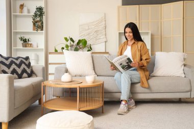 Güzel bir kadın sabahları kanepede dergi okuyor.