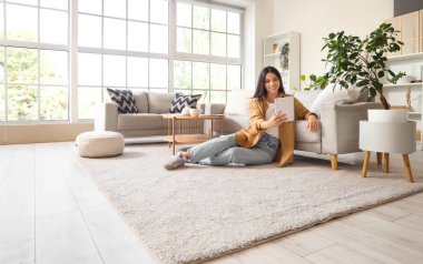 Evde tablet bilgisayar kullanan güzel bir kadın.