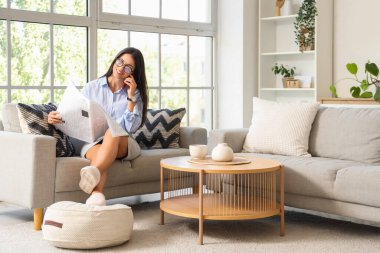 Gazetesi olan güzel bir iş kadını sabahları koltukta cep telefonuyla konuşuyor.