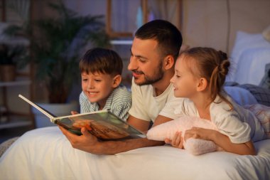 Babam ve çocukları odada kitap okuyorlar.