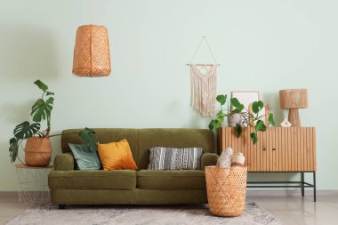 Oturma odasının içinde kanepe, çekmece ve Monstera bitkileri var.