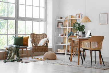 Oturma odasının içinde masa, koltuk ve yeşil bitkiler var.