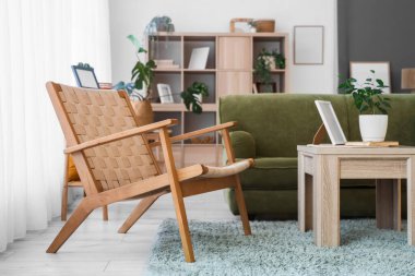 Oturma odasının içinde yeşil kanepe, koltuk ve bitkiler var.