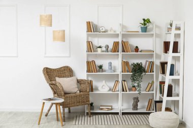 Oturma odasının içinde koltuk, bitki ve kitap rafları var.