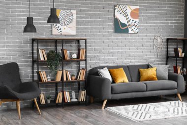 Oturma odasının içinde koltuk, kanepe ve kitaplıklar var.