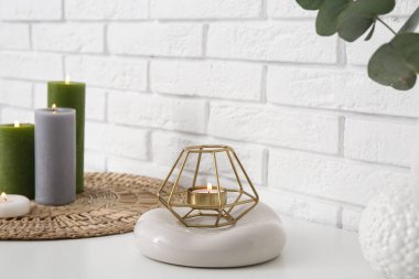 Beyaz tuğla duvarın yanındaki rafta yanan mum, yakın plan.