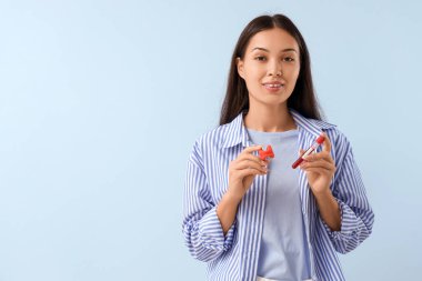 Tiroid bezi modeli olan genç bir Asyalı kadın ve mavi arka planda TSH testi için kan örneği.