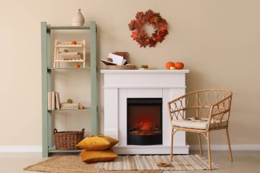 Sonbahar dekorlu şömine, raf ünitesi ve oturma odasının içindeki koltuk.