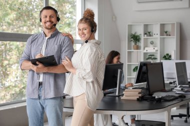 Ofiste kulaklıkları ve panosu olan teknik destek ajanları var.