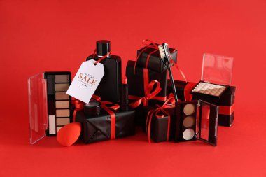 Dekoratif kozmetik ürünleri, farklı hediye kutuları ve kırmızı arka planda satış etiketi olan kompozisyon
