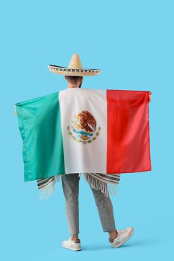 Mavi arka planda Meksika bayrağı olan şapkalı yakışıklı bir adam.