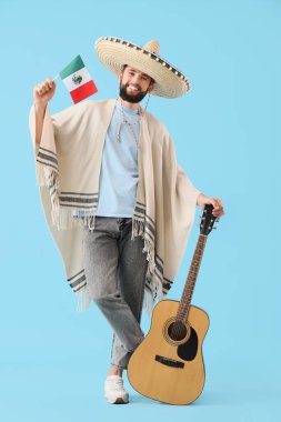 Meksika bayrağı ve mavi arka planda gitarı olan şapkalı yakışıklı bir adam.