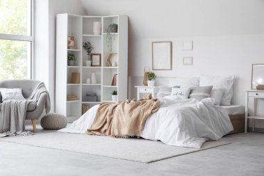 Büyük yataklı, masalı ve raf üniteli aydınlık yatak odasının içi.